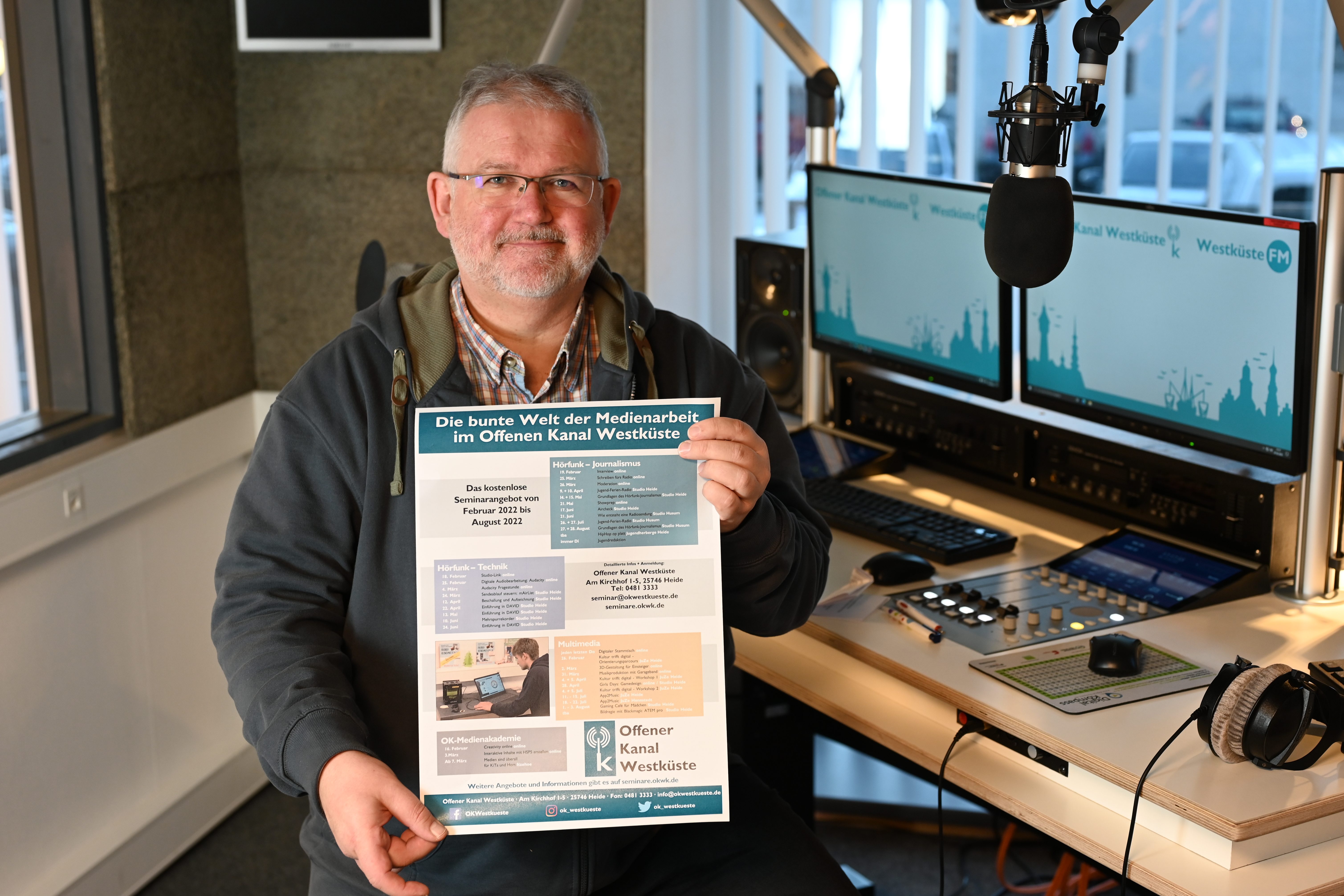 Seminarangebot OK Westküste Andreas Guballa Andreas Guballa hält das eigene Plakat mit den OK Westküste Seminaren in die Kamera