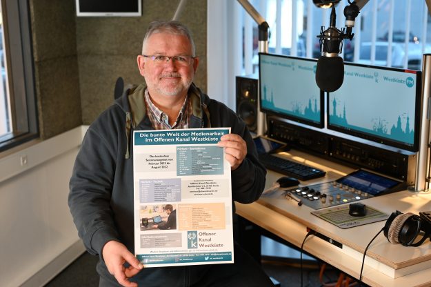 Seminarangebot OK Westküste Andreas Guballa Andreas Guballa hält das eigene Plakat mit den OK Westküste Seminaren in die Kamera
