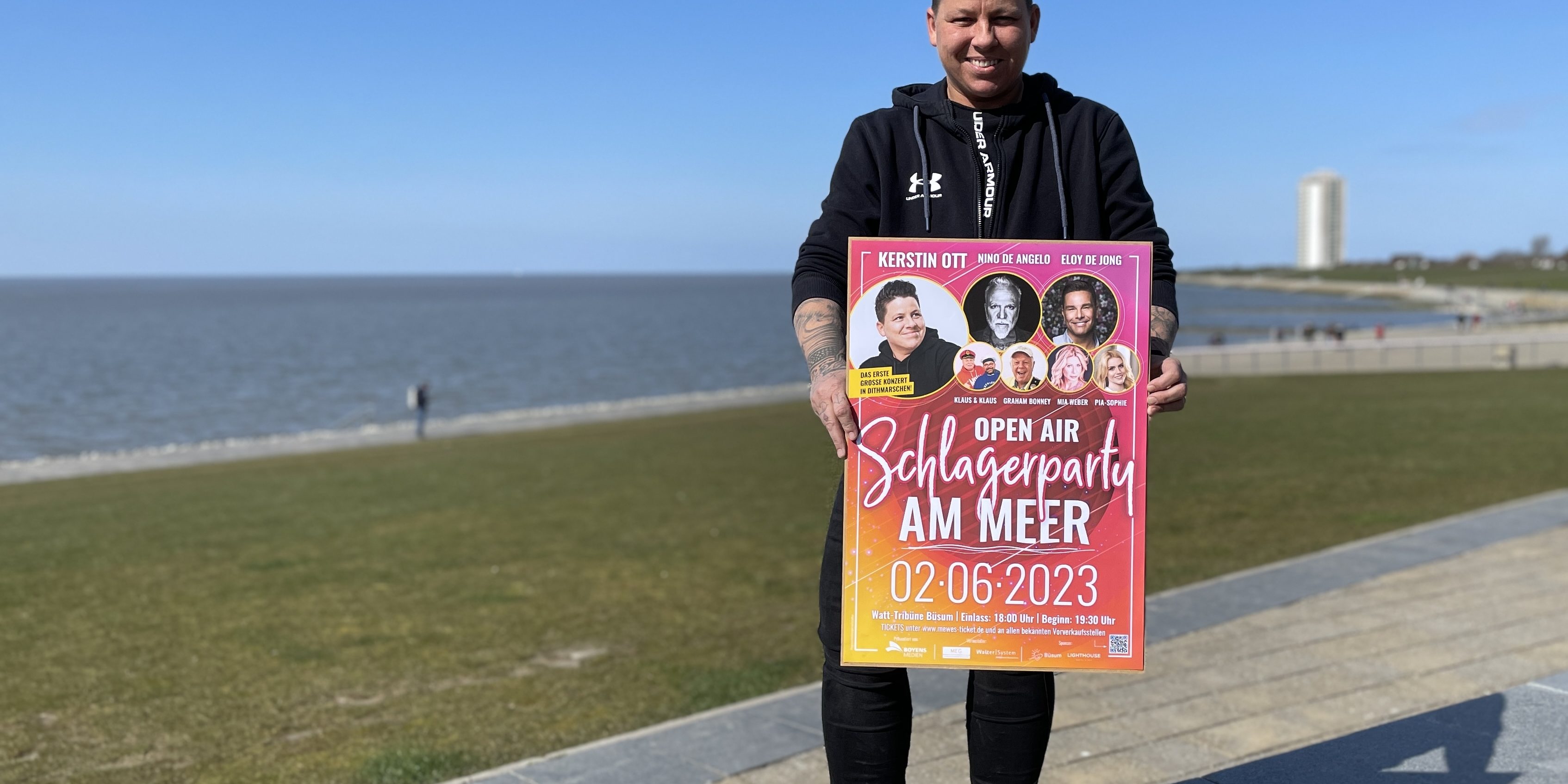 Kerstin Ott vor Schlagerparty am Meer Schlager-Pop Star Kerstin Ott vor der Büsumer Wattenmeer Kulisse. Sie hält ein Plakat in der Hand.